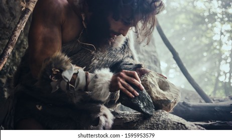 Primeval Caveman Wearing Animal Skin Hits Rock with Sharp Stone and Makes Primitive Tool for Hunting Animal Prey. Neanderthal Using Hand axe to Create first Wheel.
