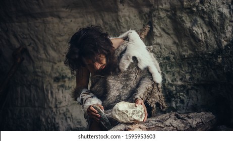 Primeval Caveman Wearing Animal Skin Hits Rock with Sharp Stone and Makes Primitive Tool for Hunting Animal Prey. Neanderthal Using Flint Rock to Create first Wheel.
