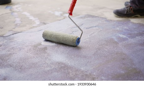 Priming the concrete floor with a roller. Professional floor primer. Leveling concrete floors. Floor repair using a primer. - Shutterstock ID 1933930646
