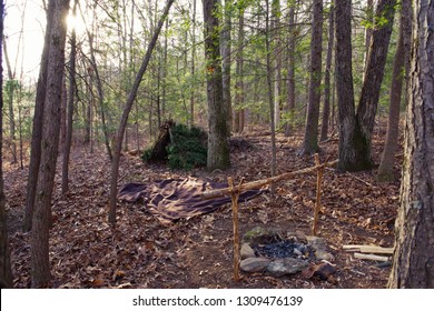 Primitive Bushcraft Survival Debris Hut With Campfire Ring Outside. Blanket, Shelter, Fire In The Forest.