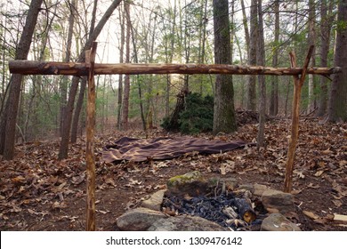 Primitive Bushcraft Survival Debris Hut With Campfire Ring Outside. Blanket, Shelter, Fire In The Forest.
