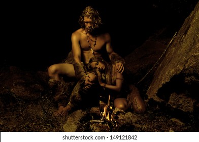 Primitive Man And His Woman Sitting Near The Fire In The Cave