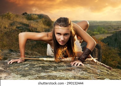 Primitive Woman On A Rock At The Sunset. Amazon Woman