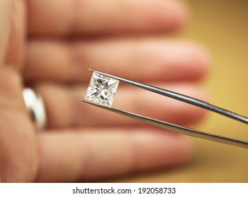 Princess cut diamond in hand held within diamond tweezers - Shutterstock ID 192058733