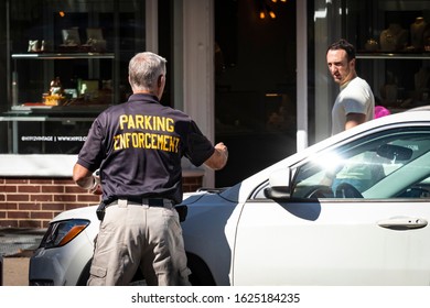 Princeton, NJ - October 4, 2019: Parking Enforcement Man Places Citation Ticket On Car - While Man Gives Him Disgusted Look