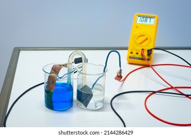 Principle of a rechargeable copper-zinc battery. Blue copper sulphate and transparent zinc sulfate are connected with a salt bridge. The voltmeter indicates just over 1 volt. Used in chemistry class.