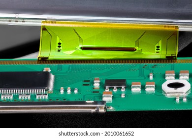 Printed Circuit Board Connected By Flexible Flat Cable To A LCD Panel. Closeup Of Electronic Components As Micro Chip, Inductor Or Capacitor On Green PCB And Plastic FPC Interface For Digital Display.