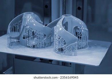 Printed models on 3D printer close-up. Objects printed on photopolymer sla 3D printer from liquid photopolymer resins on printing platform inside 3d printer. Modern progressive additive technology.