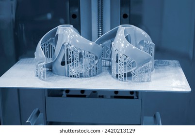 Printed models on 3D printer close-up. Objects printed on photopolymer sla 3D printer from liquid photopolymer resins on printing platform inside 3d printer. Modern progressive additive technology.