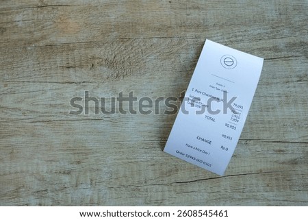 A printed restaurant receipt placed on a wooden table, including service tax and subtotal. Ideal for use in finance, retail, payment, or expenses, spending, dining, and customer service