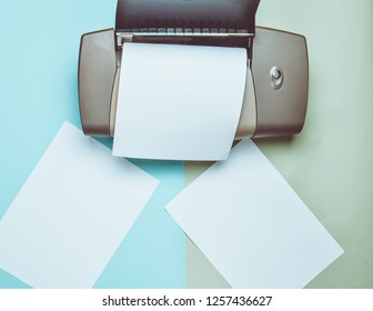 A printer with blank paper forms on a colored pastel background. Top view, flat lay.