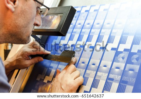 Printer looking through an eye glass to check the print plates calibration pattern