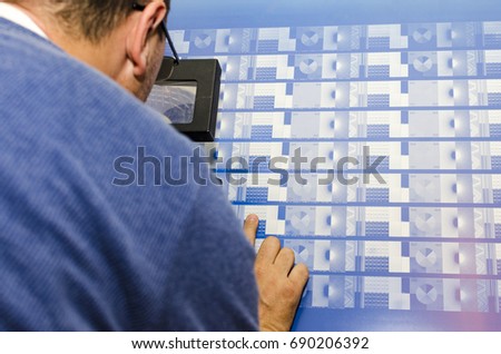 Printer looking through an eye glass to check the print plates calibration pattern