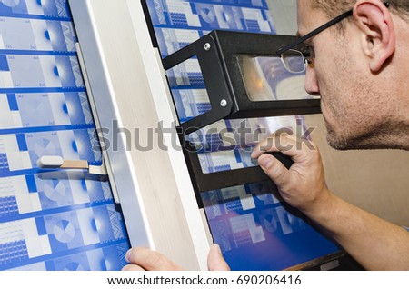 Printer looking through an eye glass to check the print plates calibration pattern