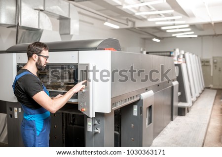 Printing operator working with offset machine at the printing manufacturing