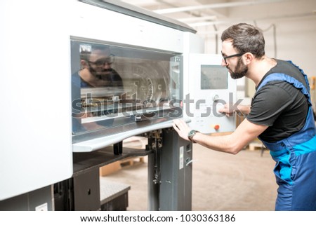 Printing operator working with offset machine at the printing manufacturing