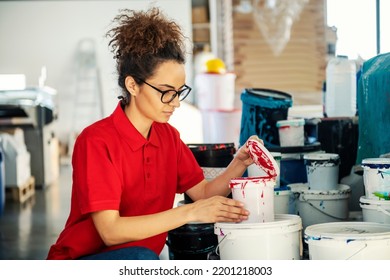 A Printing Shop Worker Kneeling And Opening Bucket With Color.