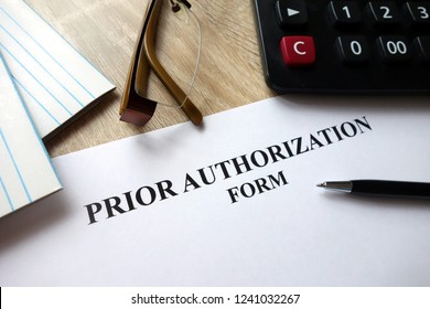 Prior Authorization Form With Pen, Calculator And Glasses On Desk