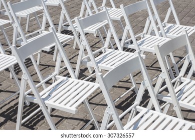 Prior to a wedding ceremony, white chairs wait for their guests.