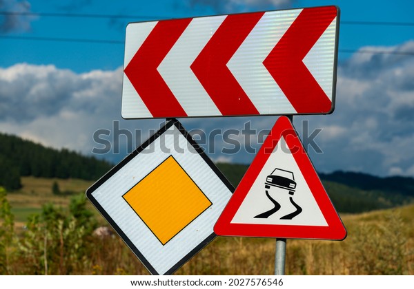 Priority, slippery road and dangerous curve at left\
road signs close up\
shot.