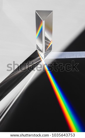 A prism dispersing sunlight splitting into a spectrum on a white background.