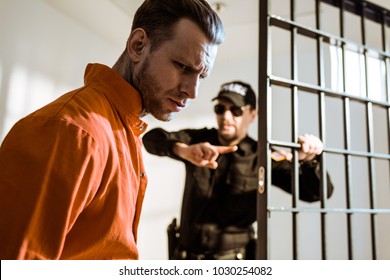 Prison Guard Showing Something To Criminal In Prison Cell