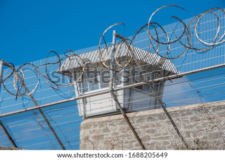 Prison Scene with razor wire foreground and guard tower in background.  Location old Fremantle Prison Western Australia.  Security fencing with razor wire watch tower.