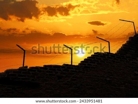 Prison wall and electric fences at sunset. freedom themed photo. 