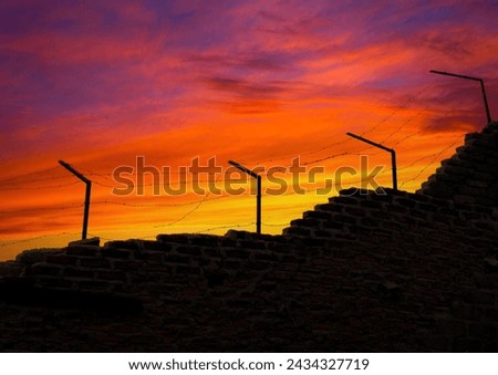 Prison wall and electric fences at sunset. freedom themed photo