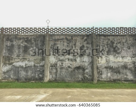 Prison wall, view of old raw concrete prison wall with old brick on top and silver after the the rain sky as a background