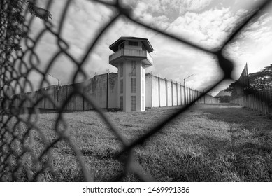 Тюремная сторожевая башня, защищенная проволокой тюремного ограждения. Белая тюремная стена и сторожевая башня со спиральной колючей проволокой. Концепция тюремного заключения в уголовном правосудии