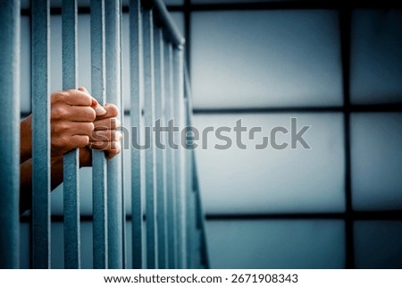 A prisoner behind the jail cell bars .