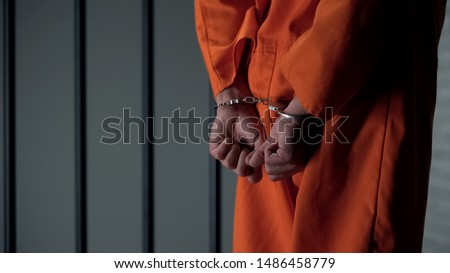 Prisoner with handcuffed arms behind back, another jail transfer, criminal