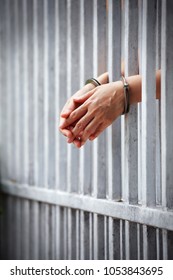 prisoner hands behind jail bar background.