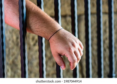 Prisoner Man Holding Hands On Jail Bars. Hands On Prison Bars.