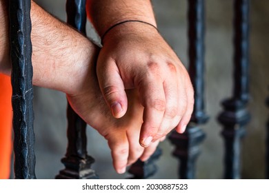 Prisoner Man Holding Hands On Jail Bars. Hands On Prison Bars.