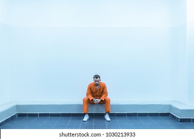 prisoner sitting on bench in prison room