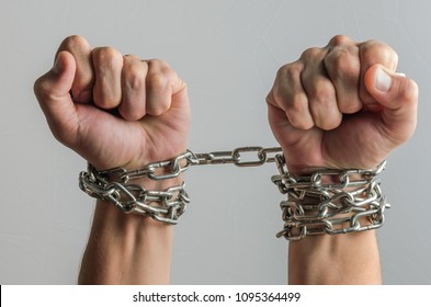 The prisoner's hands are bound in metal chains