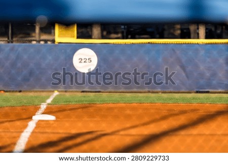 A pristine baseball field awaits the first pitch of the day, with perfectly striped green grass, crisp chalk lines, and rich brown infield dirt glowing in the soft morning light before the game begins.