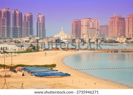 Pristine beach shoreline in Doha extending along the water, with modern high rise buildings and mosque architecture dominating the cityscape