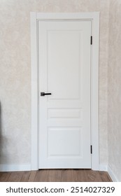A pristine and immaculate white door featuring a sleek and elegant handle, beautifully set against a soft beige wall, making it ideal for modern contemporary interior designs
