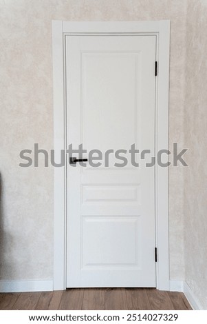 A pristine and immaculate white door featuring a sleek and elegant handle, beautifully set against a soft beige wall, making it ideal for modern contemporary interior designs
