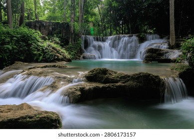 A pristine multitiered waterfall flows into a crystal clear emerald pool within the dense tropical jungle of huai mae khamin waterfall in kanchanaburi thailand.