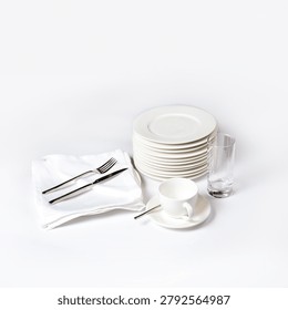 A pristine stack of white ceramic plates accompanied by polished silverware on a linen napkin, a coffee cup, and a glass