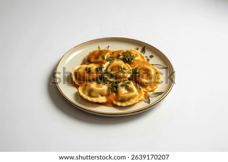 a pristine white ceramic plate piled high with a generous portion of golden-brown ravioli.