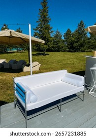 A pristine white couch is positioned elegantly on a wellcrafted wooden deck, providing a stylish and comfortable seating solution for outdoor relaxation and enjoyment of natures beauty