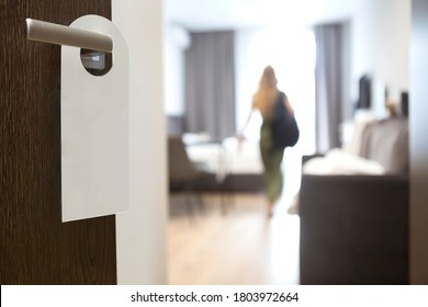 Privacy Sign Hanging On Handle Of Open Door To Hotel Room With Standing Person. Copy Space.