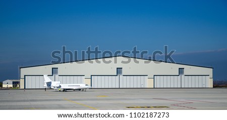 Private aviation. Hangar and a small plane on concrete.