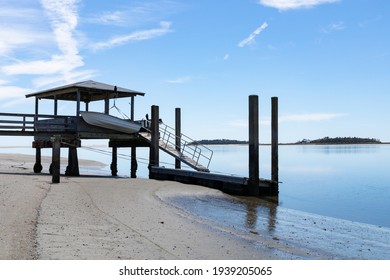 Private Boat Dock On Tybee Creek At The Atlantic Ocean, Sandy Beach And Still Blue Waters Beneath A Bright Blue Sky With Clouds, Tybee Island Georgia, Horizontal Aspect