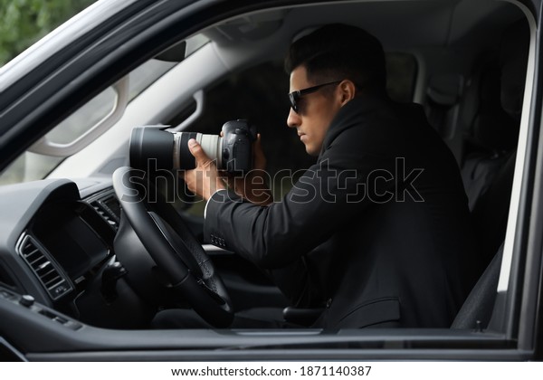 Private detective\
with camera spying from\
car